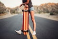 Beautiful girl with long legs enjoys a ride on a longboard at summertime. Outdoors sports activities.