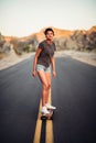 Beautiful girl with long legs enjoys a ride on a longboard at summertime. Outdoors sports activities.