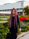 Beautiful girl with long pink dreadlocks in black clothes with a backpack walks around the city Royalty Free Stock Photo