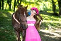 Beautiful girl in long pink dress near big brown horse Royalty Free Stock Photo