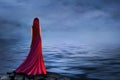 Beautiful girl in a long red dress stands by the river with fog Royalty Free Stock Photo
