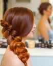 Beautiful girl with long red hair, braided with a French braid, in a beauty salon. Royalty Free Stock Photo