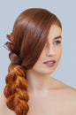 Beautiful girl with long red hair, braided with a French braid, in a beauty salon. Royalty Free Stock Photo
