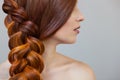 Beautiful girl with long red hair, braided with a French braid, in a beauty salon Royalty Free Stock Photo