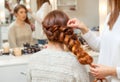 Beautiful girl, with long, red-haired hairy. hairdresser weaves a French braid, close-up Royalty Free Stock Photo