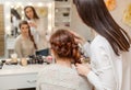 Beautiful girl, with long, red-haired hairy. hairdresser weaves a French braid, close-up in a beauty salon. Royalty Free Stock Photo