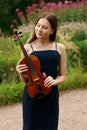 a beautiful girl with long violinists stands in the park in the summer