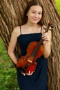 a beautiful girl with long violinists stands in the park in the summer