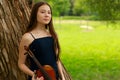 a beautiful girl with long violinists stands in the park in the summer