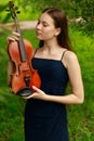 a beautiful girl with long violinists stands in the park in the summer