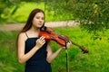 a beautiful girl with long violinists stands in the park in the summer