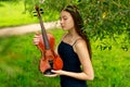 a beautiful girl with long violinists stands in the park in the summer