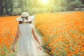 Beautiful girl in a long white dress of enjoying a walk in the park at retro flowers background