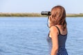 Beautiful girl looking through binoculars on the river Royalty Free Stock Photo