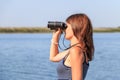 Beautiful girl looking through binoculars on the river Royalty Free Stock Photo