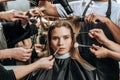 Beautiful girl looking at camera while stylists applying makeup and doing hairstyle