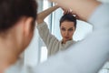 Girl looking in the mirror while making ponytail Royalty Free Stock Photo