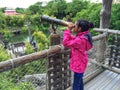 A beautiful girl looking through a telescope at the park.