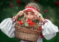 A beautiful girl looks through a basket with Rowan berries in her hands and smiles Royalty Free Stock Photo