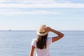 Beautiful girl looks at the sea. Young girl in a hat looking at a calm sea and blue skies Royalty Free Stock Photo