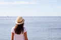 Beautiful girl looks at the sea. Young girl in a hat looking at a calm sea and blue skies Royalty Free Stock Photo
