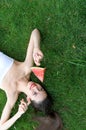 Beautiful girl lying on the grass and eats watermelon