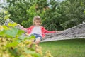 Beautiful girl lying on hammock, smiling resting child in spring garden Royalty Free Stock Photo
