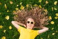 Beautiful girl lying on lawn with yellow leaves in autumn park Royalty Free Stock Photo