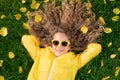 Beautiful girl lying on lawn with yellow leaves in autumn park Royalty Free Stock Photo