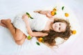 Beautiful girl lying among tangerines