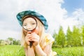 Beautiful girl with magnifier laying on the grass