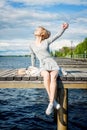 Beautiful girl makes selfie. All alone, she sits on a river pier, the wind spreads blond hair in different directions. Royalty Free Stock Photo