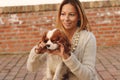 Beautiful girl is making hearts to her dog Cavalier King Charles Spaniel on the red brick stairs Royalty Free Stock Photo