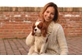 Beautiful girl is making rabbit ears to her dog Cavalier King Charles Spaniel on the red brick stairs Royalty Free Stock Photo