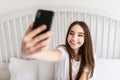 Beautiful girl making selfie in the bed. Beautiful girl making self on the bed at home. Selfie in the morning Royalty Free Stock Photo