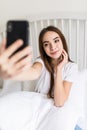 Beautiful girl making selfie in the bed. Beautiful girl making self on the bed at home. Selfie in the morning Royalty Free Stock Photo