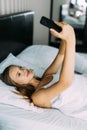 Beautiful woman making selfie in the bed. Beautiful girl making self on the bed at home. Selfie in the morning Royalty Free Stock Photo