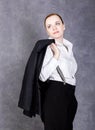 Beautiful girl in man`s suit, white shirt and suspenders poses on a gray background Royalty Free Stock Photo