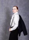 Beautiful girl in man`s suit, white shirt and suspenders poses on a gray background Royalty Free Stock Photo