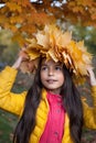 Beautiful girl in maple leaves wreath, fall park
