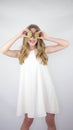 A beautiful girl of model appearance with fruits in her hands,holding a kiwi,in a white dress On a white background Royalty Free Stock Photo