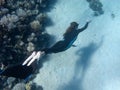 Beautiful girl with monofin swims near coral reef