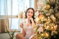 Beautiful girl in the morning with a cup in the New Year`s interior. Woman at home at Christmas time in a bedroom in a rustic styl Royalty Free Stock Photo