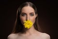 Beautiful girl with natural make-up bare shoulders holding a flower in her mouth with a beauty skin and long hair Royalty Free Stock Photo