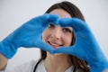 beautiful young girl nurse showing heart in blue gloves doctor surgery helping people care treatment hippocratic oath