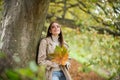 Beautiful girl outdoors in autumn fall. Young woman collects yellow fall leaves in autumn. Beauty woman holds autumn Royalty Free Stock Photo