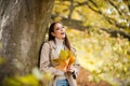 Beautiful girl outdoors in autumn fall. Young woman collects yellow fall leaves in autumn. Beauty woman holds autumn Royalty Free Stock Photo