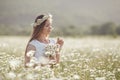 Beautiful woman in a wreath of real flowers, with a bouquet in a field of white daisies Royalty Free Stock Photo