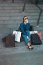 Beautiful girl with paper bags sits on a stairs outside shopping mall Royalty Free Stock Photo