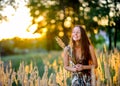 Beautiful girl in the park on a sunset, collects a bouquet from beautiful magnificent blades